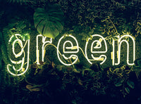 The word Green in fluorescent lights amongst green foliage